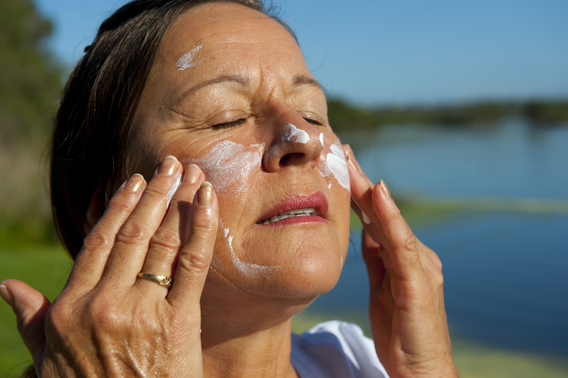 Woman applying sunscreen to her face outdoors
