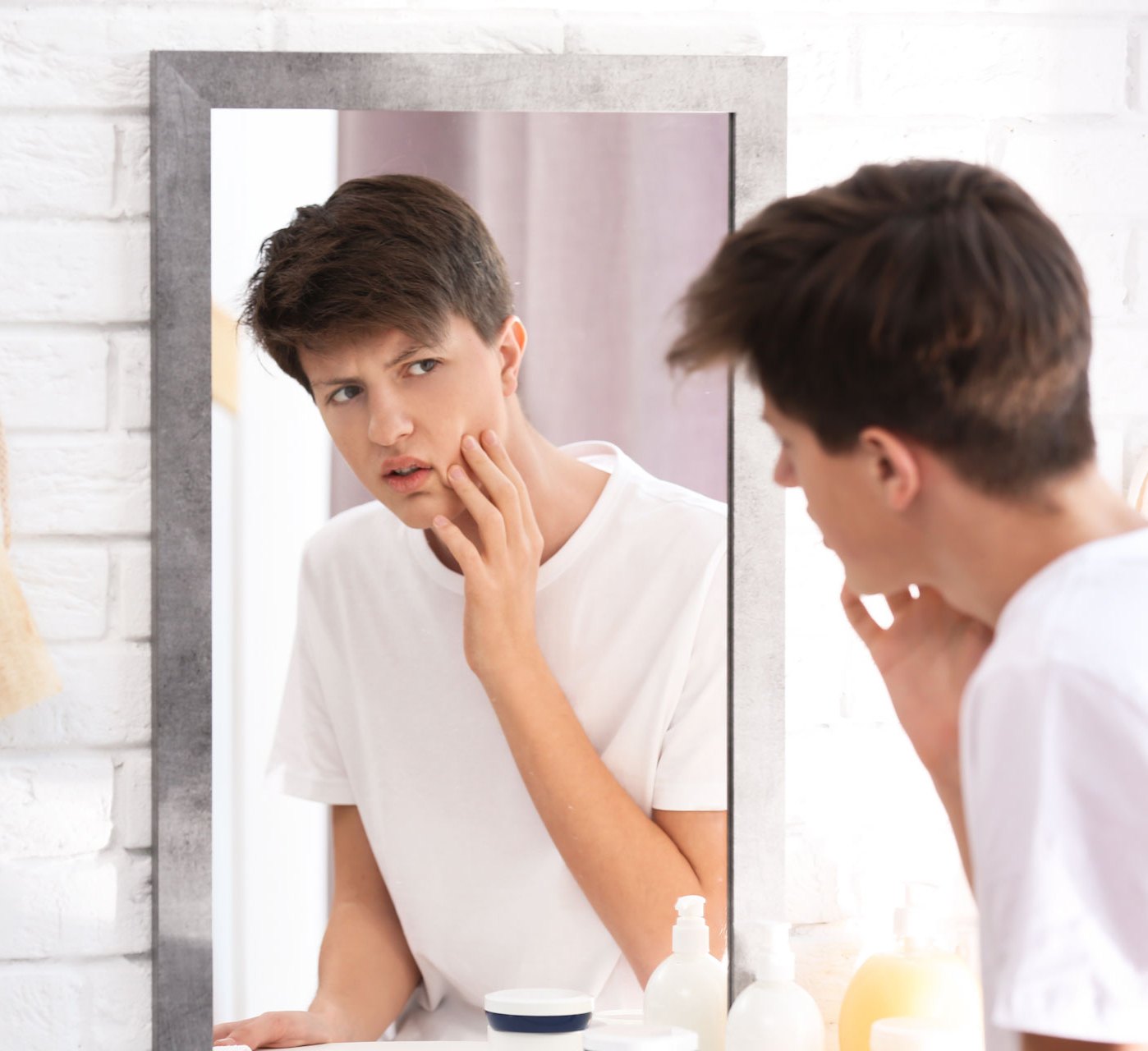 Teenage patient examining acne in the mirror before a dermatology visit
